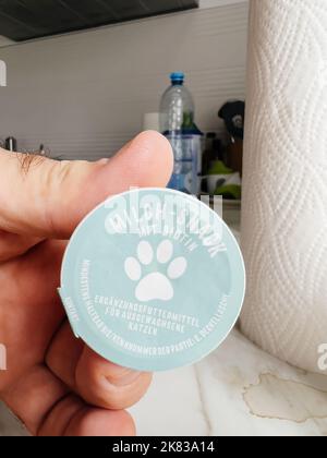 Paris, France - 13 septembre 2022: POV main mâle tenant Milch-snack avec biotine nourriture pour chats - cuisine moderne fond se préparant à nourrir l'animal de chat Banque D'Images