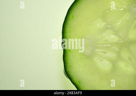 Une tranche de concombre frais se ferme sur fond vert. Macro-photographie. Banque D'Images