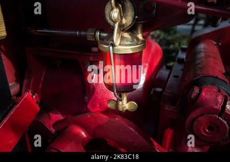 Une pompe d'aspiration de carburant en verre sur un tracteur d'époque. Banque D'Images