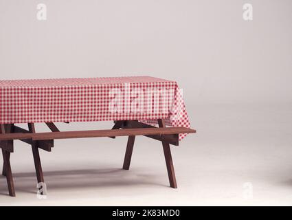 Table en bois et serviette rouge pour les fêtes en plein air et fond blanc. Banque D'Images