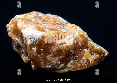 Macro pierre de calcite orange brute isolée sur fond noir Banque D'Images