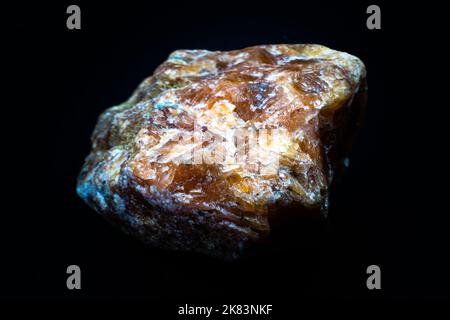 Macro pierre de calcite orange brute isolée sur fond noir Banque D'Images