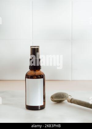 Masseur à cadran avec eau sha, bouteille d'huile essentielle ou de sérum sur fond de mur de carreaux blancs. Concept de traitement naturel. Vue avant. Copier l'espace Banque D'Images