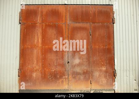 Grandes portes rouillées. Entrée pour camions. Portes fermées dans la zone industrielle. Grand mur de hangar. Banque D'Images