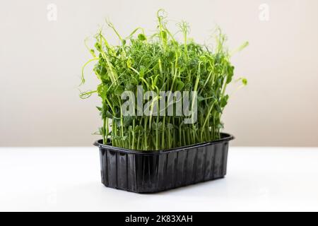 Micro pousses de pois verts sur une table blanche pour une alimentation saine Banque D'Images