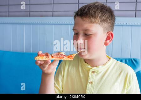 Un garçon mange de la pizza italienne dans un café. Gros plan Banque D'Images