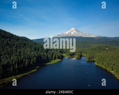 Paysage charmant. Calme rivière bleu foncé, sur la rive d'une forêt de pins. Haute montagne couverte de neige. Ciel bleu avec nuages blancs clairs. Carte postale, tra Banque D'Images