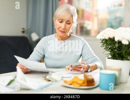 Femme âgée avec des documents financiers à la maison Banque D'Images