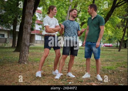 Trois beaux jeunes hommes s'amusent dans un parc Banque D'Images