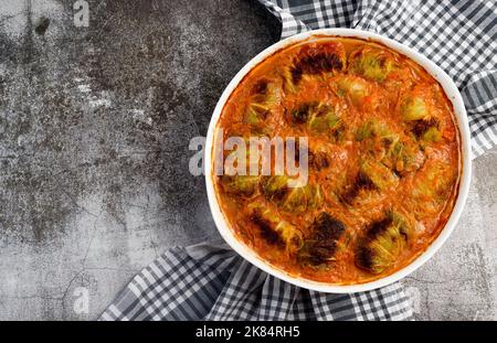 Roulés de chou farcis avec de la viande et du riz dans un plat blanc sur fond gris foncé. Vue de dessus, plan d'appartement Banque D'Images