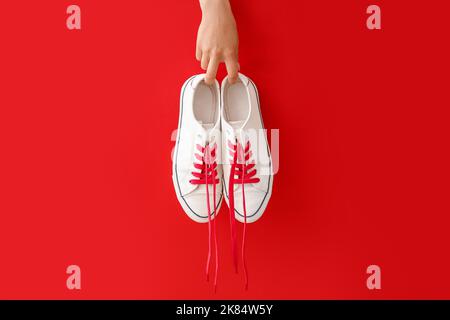 Femme tenant des baskets avec lacets rouges sur fond de couleur Banque D'Images