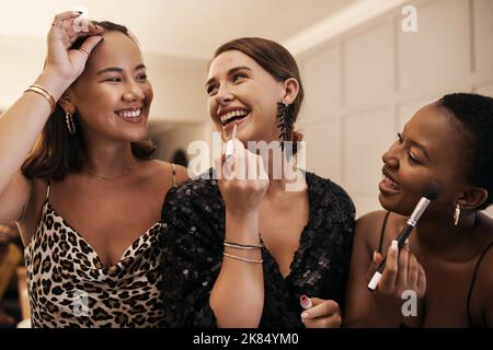 Un groupe diversifié d'amis se tenant ensemble et se maquillant lors d'un dîner du nouvel an. Banque D'Images