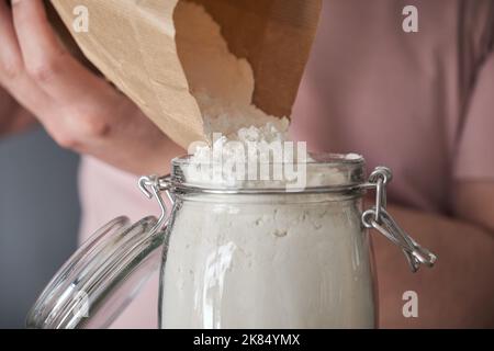 latins méconnaissables remplissant un pot de farine de blé dans un sac en papier. Banque D'Images