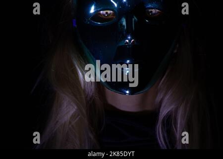 visage d'une fille dans un masque de carnaval dans l'obscurité, un homme dans un masque, masque de carnaval Banque D'Images