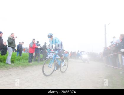 Un pilote Movistar sorti du nuage de poussière a lancé un dur coin pavé lors de la course Paris Roubaix 2019 à Paris, France sur 14 avril 2019. Banque D'Images