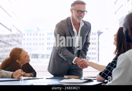 Un mouvement de pouce vous rapproche de miles d'intention : un homme d'affaires mature et une femme d'affaires qui se secouent la main lors d'une réunion dans un bureau moderne Banque D'Images
