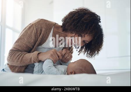 Quel pur contentement ressemble. Une jeune femme jouant avec son adorable bébé fille sur le lit à la maison. Banque D'Images