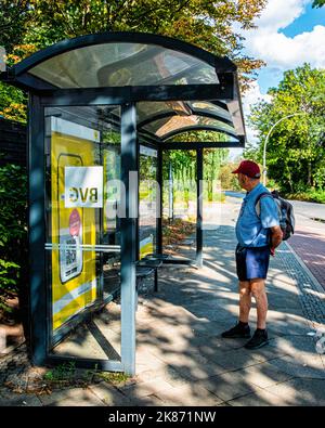 Un homme âgé portant un sac à dos attend à l'arrêt de bus à Neuköllnische Allee, Neukölln, Berlin Banque D'Images