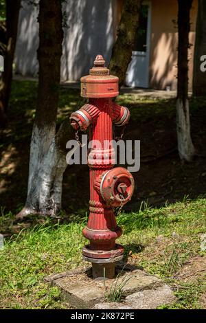 Borne d'eau rustique de couleur rouge sur le campus étudiant de Petrosani Banque D'Images