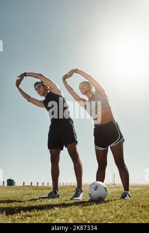 Couple de football s'étirant au parc, les gens s'entraînent sur un terrain de football en plein air ou en entraîneur pour un objectif sportif. La motivation physique ensemble Banque D'Images