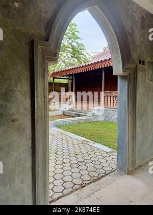 Façade d'une maison en bois javanaise traditionnelle encadrée par une porte en béton Banque D'Images