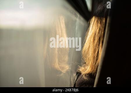 La fille est assise par le verre sur le bus. Cheveux pour fille par fenêtre. Dans le bus. Passager en transport. Homme devant sur le siège. Banque D'Images