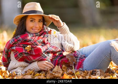 Portrait d'une jeune femme heureuse en tenue d'automne pendant la chute des feuilles. Banque D'Images