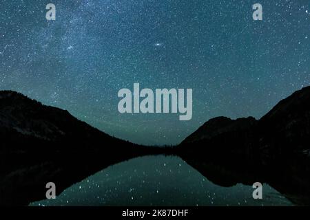 Le lac Toxaway, situé dans la région sauvage de Sawtooth dans l'Idaho, vu pendant une nuit d'été avec de nombreuses étoiles dans le ciel et réfléchi à la surface de l'eau. Banque D'Images