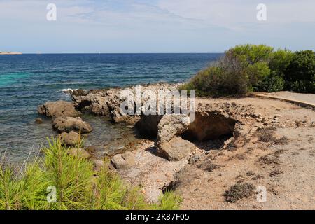Vue idyllique d'une plage rocheuse avec végétation verte en premier plan et en arrière-plan, Cala Ratjada, Majorque Banque D'Images