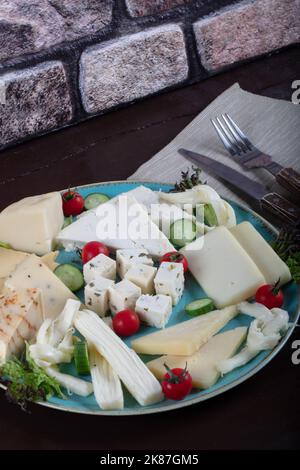 Assiette de fromages sur une table sombre. Plusieurs sortes de fromage sur une assiette Banque D'Images