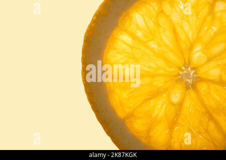 Une tranche de fruits frais d'orange juteuse se rapproche de l'arrière-plan de l'espace de copie orange clair. Macro-photographie. Banque D'Images