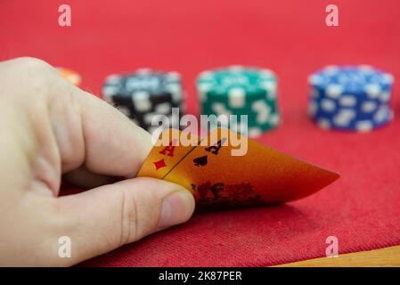 Cartes de jeu en main sur le tissu rouge. Une combinaison gagnante dans Poker Texas Holdem. Deux as et un gros piquet sur du feutre rouge. Deux as sur la table de poker an Banque D'Images