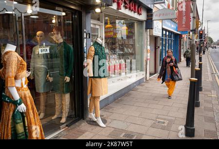 Une femme marche à côté d'un magasin vendant des saris et des vêtements traditionnels d'Asie du Sud à Belgrave Road, Leicester. Banque D'Images