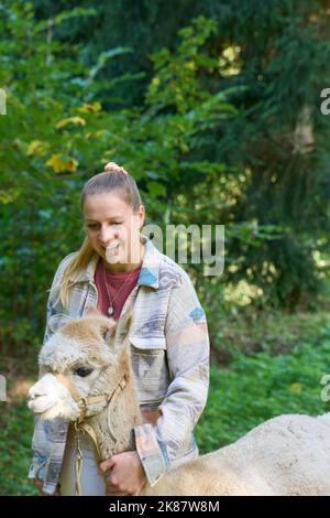 Un Sunbeam rencontre une jeune femme avec beige Alpaca sur Forest Path. Dans la Forêt verte de fond. Bauma, Oberland de Zurich, Suisse Banque D'Images