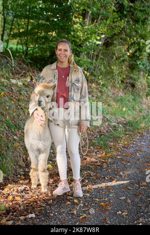 Un Sunbeam rencontre une jeune femme avec beige Alpaca sur Forest Path. Dans la Forêt verte de fond. Bauma, Oberland de Zurich, Suisse Banque D'Images