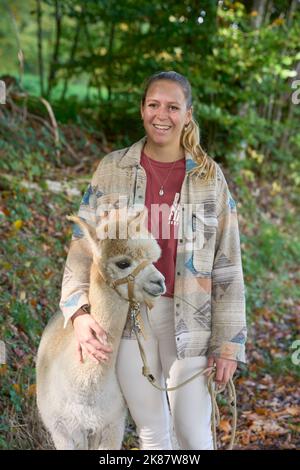 Un Sunbeam rencontre une jeune femme avec beige Alpaca sur Forest Path. Dans la Forêt verte de fond. Bauma, Oberland de Zurich, Suisse Banque D'Images