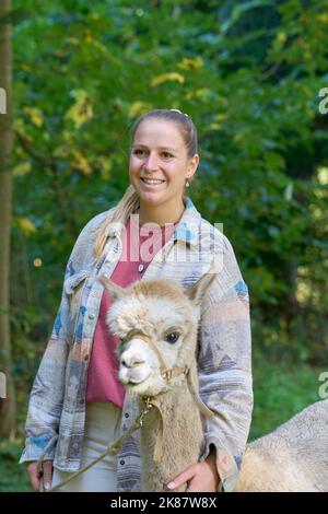 Un Sunbeam rencontre une jeune femme avec beige Alpaca sur Forest Path. Dans la Forêt verte de fond. Bauma, Oberland de Zurich, Suisse Banque D'Images