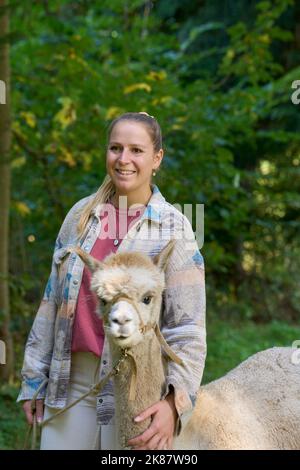 Un Sunbeam rencontre une jeune femme avec beige Alpaca sur Forest Path. Dans la Forêt verte de fond. Bauma, Oberland de Zurich, Suisse Banque D'Images