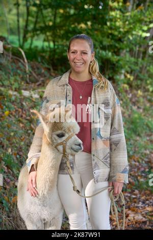 Un Sunbeam rencontre une jeune femme avec beige Alpaca sur Forest Path. Dans la Forêt verte de fond. Bauma, Oberland de Zurich, Suisse Banque D'Images