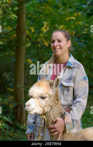 Un Sunbeam rencontre une jeune femme avec beige Alpaca sur Forest Path. Dans la Forêt verte de fond. Bauma, Oberland de Zurich, Suisse Banque D'Images