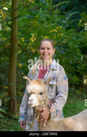 Un Sunbeam rencontre une jeune femme avec beige Alpaca sur Forest Path. Dans la Forêt verte de fond. Bauma, Oberland de Zurich, Suisse Banque D'Images