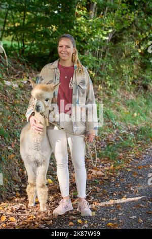 Un Sunbeam rencontre une jeune femme avec beige Alpaca sur Forest Path. Dans la Forêt verte de fond. Bauma, Oberland de Zurich, Suisse Banque D'Images