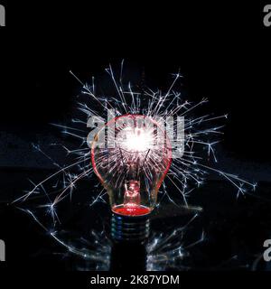 Une ampoule avec des étincelles qui s'en échappent sur un fond noir Banque D'Images