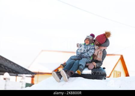 Famille maman et enfant activité d'hiver, glisse de la colline de neige toget Banque D'Images