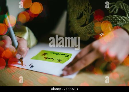 Kid écrit une lettre au Père Noël avec bokeh lumineux de noël Banque D'Images