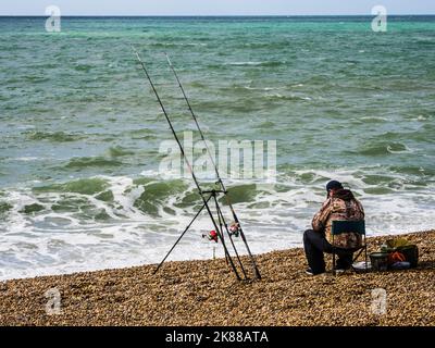 Un pêcheur solitaire sur la plage de Chesil à Dorset. Banque D'Images