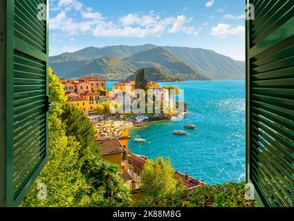 Vue par une fenêtre ouverte avec des volets donnant sur le village pittoresque et coloré de Varenna, en Italie, sur les rives du lac de Côme en été. Banque D'Images