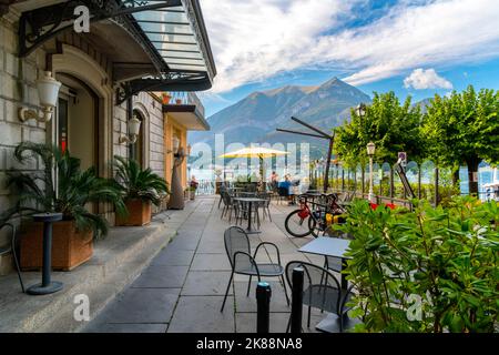 Les touristes dînent dans un café en plein air au bord du lac de Côme en été dans la ville pittoresque de Bellagio, en Italie. Banque D'Images