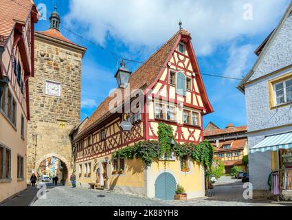 Une rue pittoresque de bâtiments à colombages avec des boutiques et des maisons le long d'une tour d'entrée de ville dans le village de Rothenburg, en Allemagne du Tauber Banque D'Images