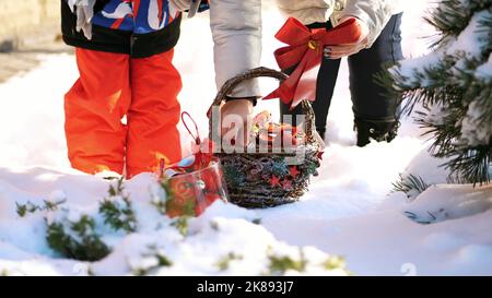 hiver, givré, enneigé, ensoleillé jour. Une famille heureuse avec de petits enfants décorent l'arbre de Noël à l'extérieur avec des décorations de Noël. Photo de haute qualité Banque D'Images